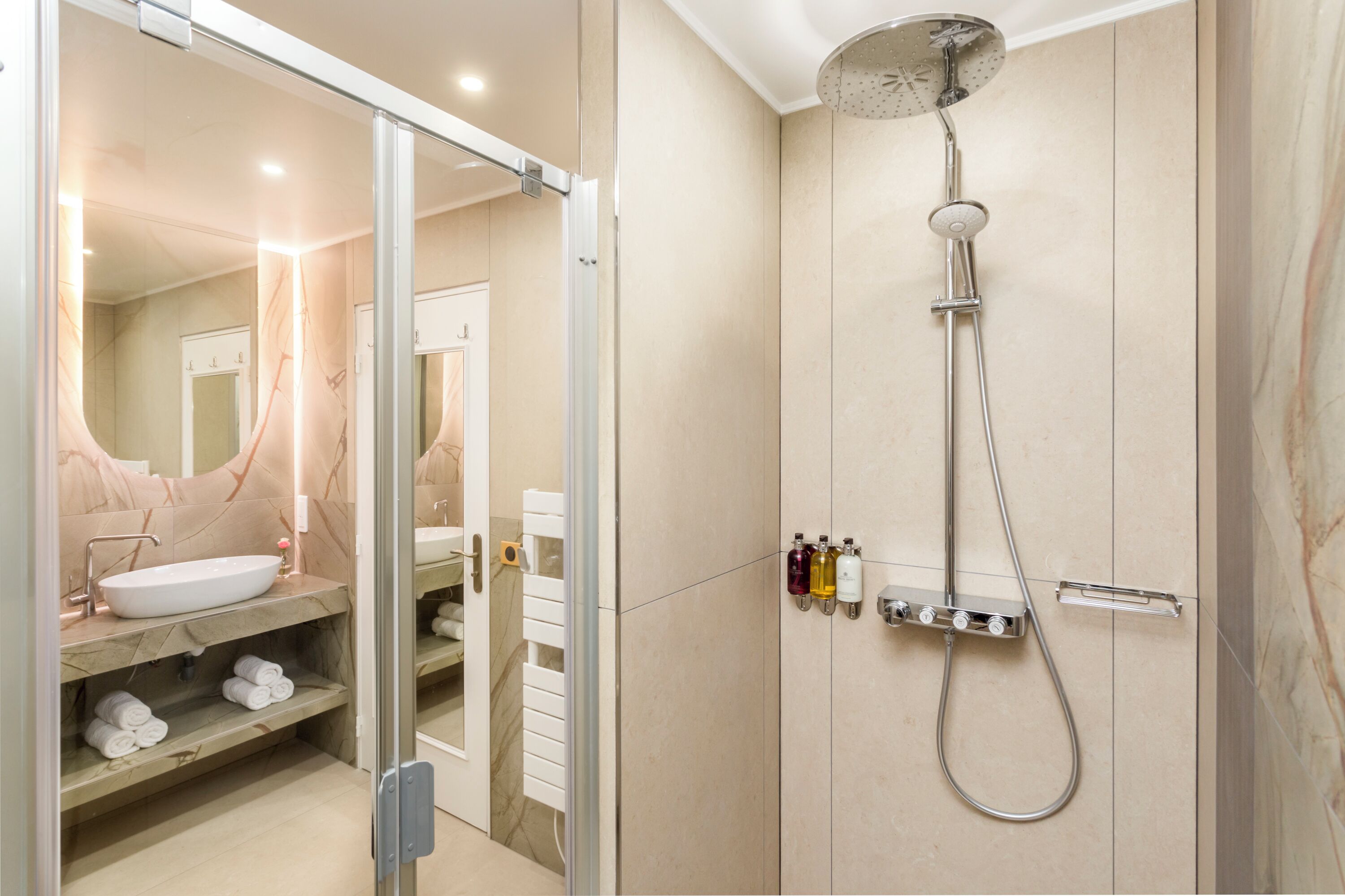 A modern bathroom with a glass shower enclosure, a sink with a marble countertop, and a mirror.