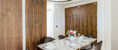 A dining area with a marble table, six chairs, and a chandelier.