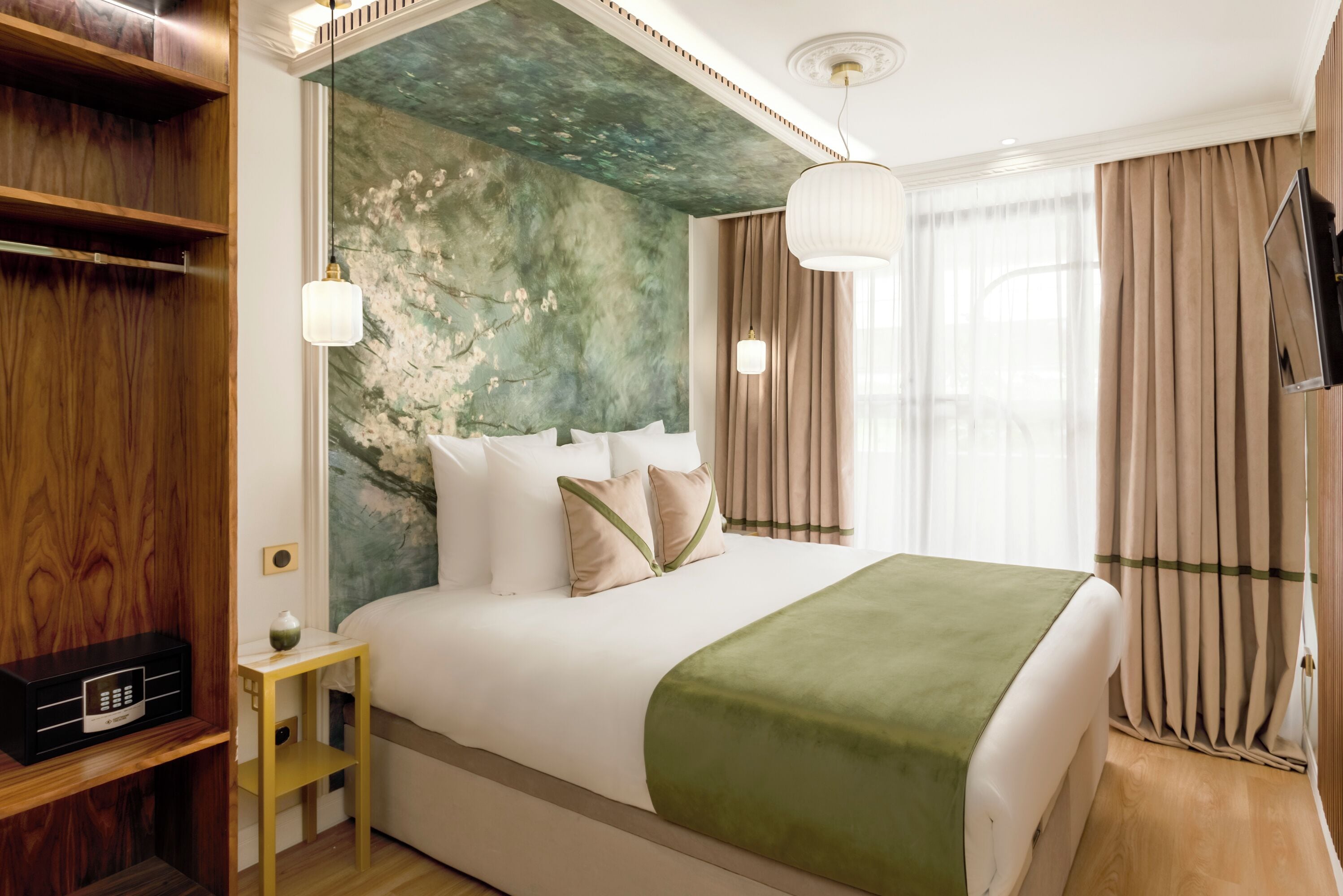 Una habitación de hotel ordenada con una cama grande, un armario de madera y un televisor en la pared.