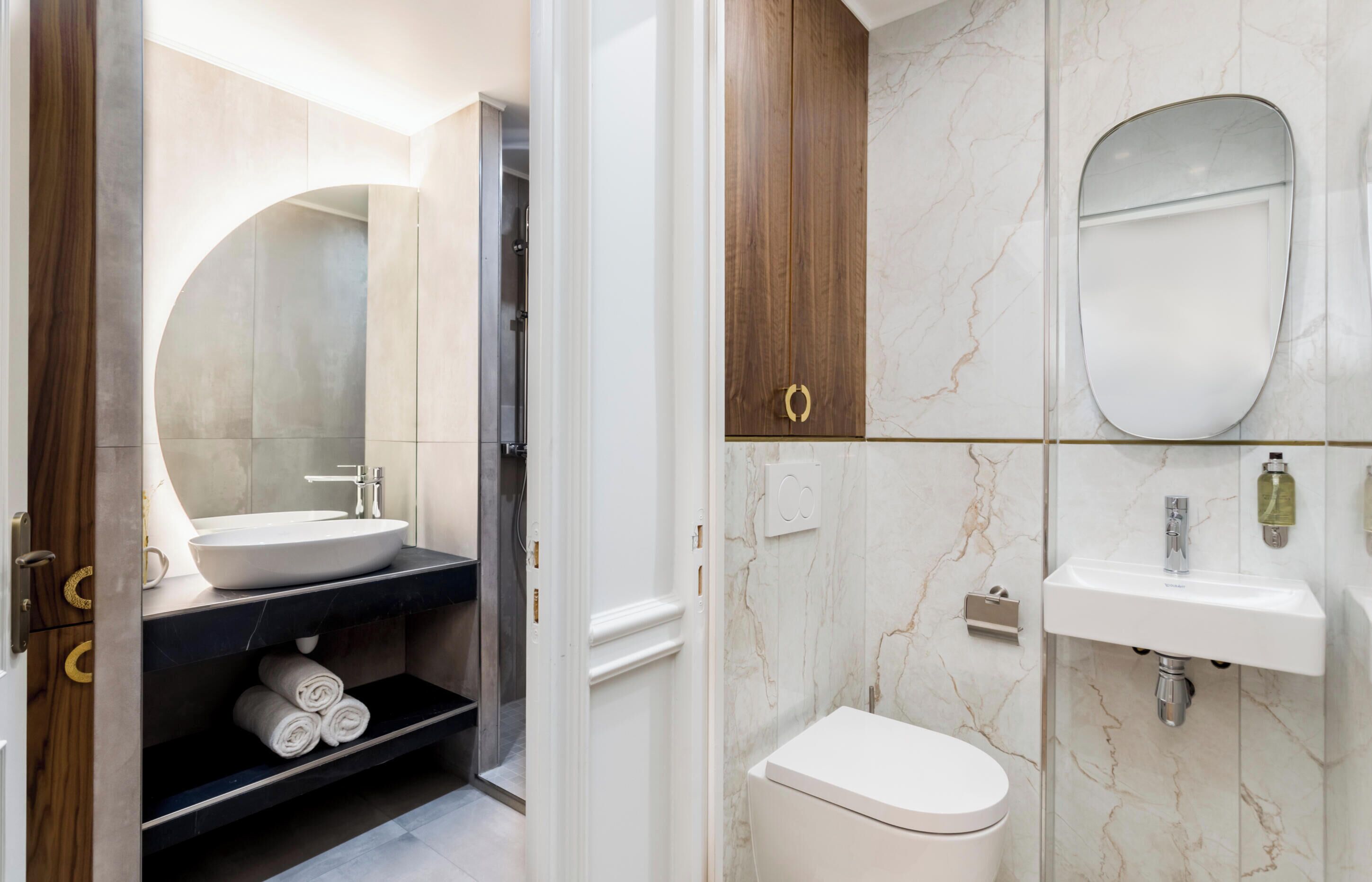 A modern bathroom with a vanity, sink, toilet, and a large mirror.