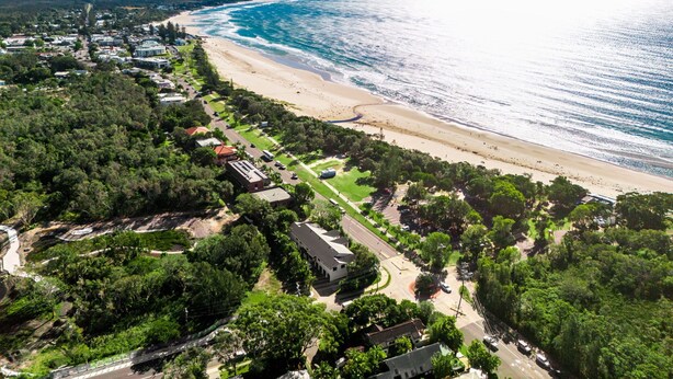 An aerial view of a coastal town with a beach, residential areas, and a mix of greenery and buildings. - Bianca's- Stunning, Stylish & Steps from the Beach (Byron Bay)