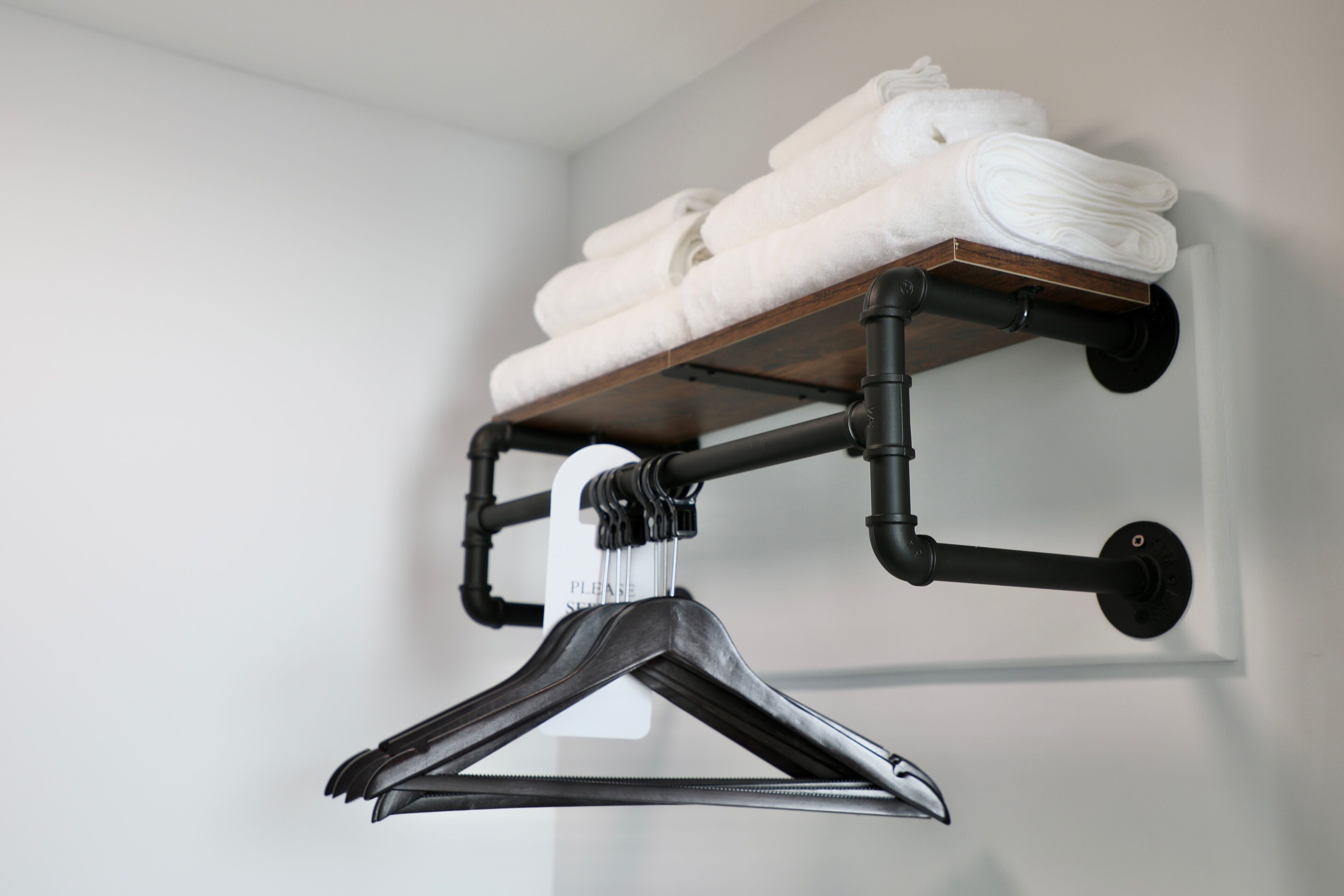 Un toallero de pared con toallas dobladas y un perchero negro.