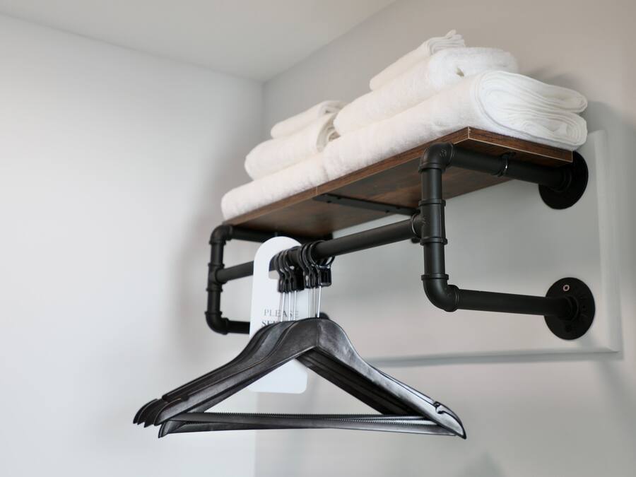 A wall-mounted towel rack with folded towels and a black hanger.
