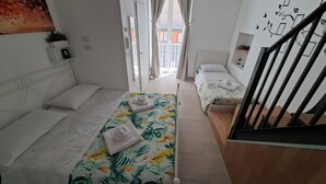 Habitación de hotel con dos camas individuales, piso de madera, una escalera y vistas al exterior.