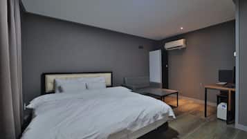 Una camera d'albergo con un letto, una scrivania, una sedia e un condizionatore d'aria.