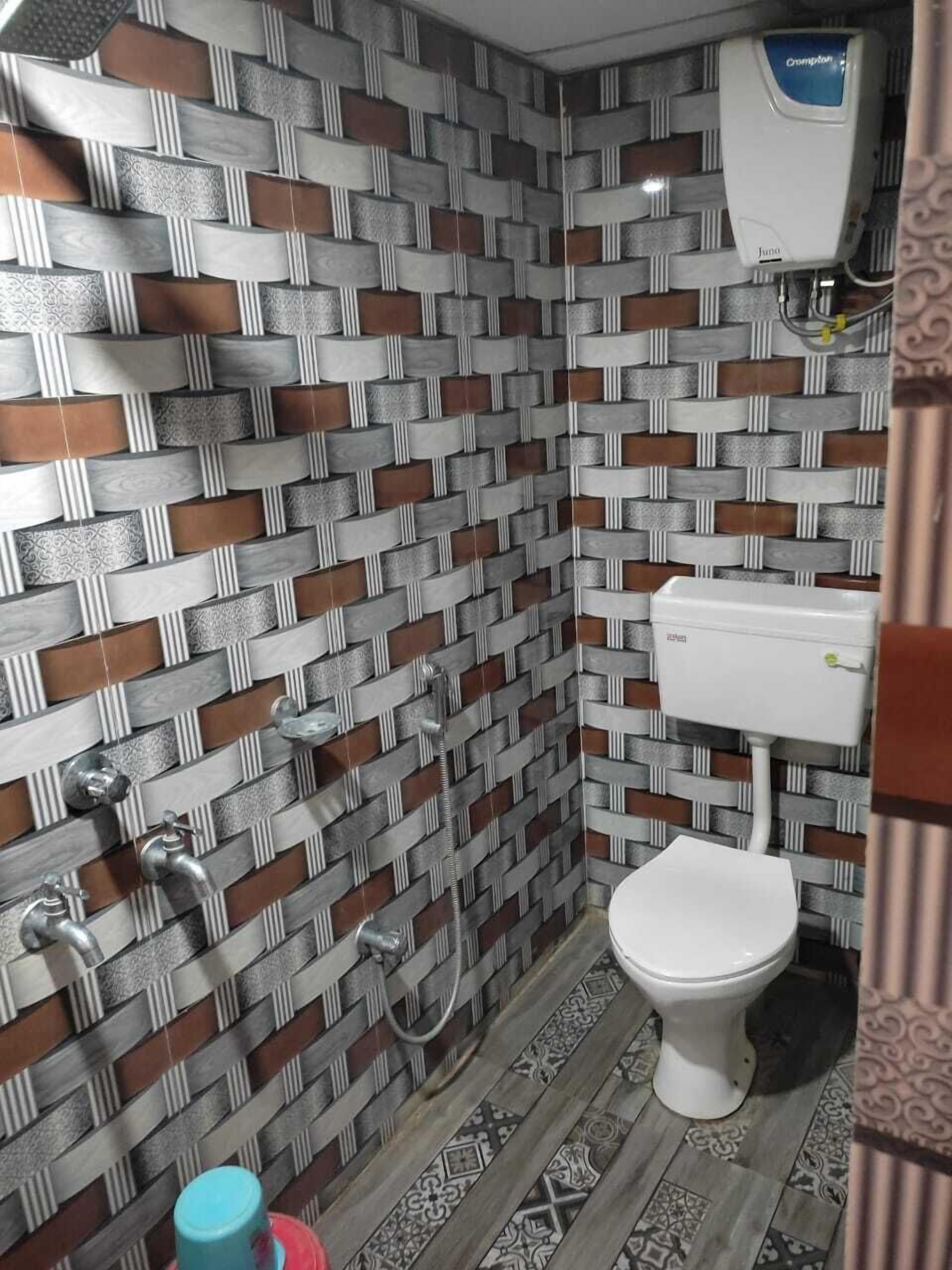 A bathroom with a patterned tile wall, a toilet, a sink, and a shower.