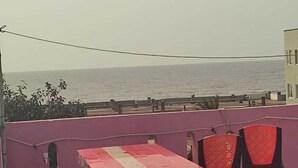 A table and chairs set up on a balcony with a view of the sea. - Deteex Hotel Baluchar (Mandarmani)