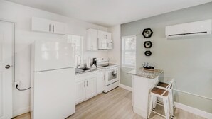 A modern kitchen with white cabinetry, a built-in oven, and a small island with stools.
