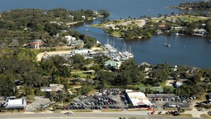 An aerial view of a coastal area with a marina, parked cars, and buildings.