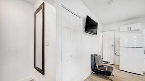 A modern kitchen with white cabinets, a built-in LG refrigerator, and a flat-screen TV mounted above the counter.