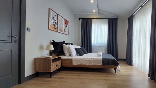A modern bedroom with a wooden bed, bedside tables, and artwork on the wall.