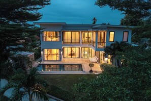 A modern two-story house with a swimming pool, large windows, and a well-maintained garden. - One of Phukets Best Villas V212 (Si Sunthon)