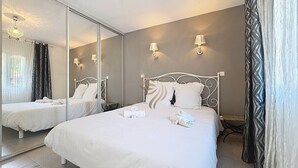 Een hotelkamer met een groot bed, een spiegel, twee nachtkastjes en een wandlamp.