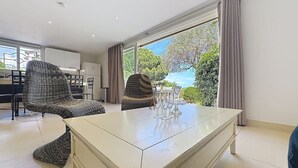 Een moderne woonkamer met een groot raam, een eethoek en een zithoek.
