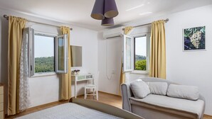 Une chambre à coucher comprenant un lit, un bureau, une chaise, un canapé et deux fenêtres avec des rideaux.