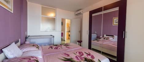 A bedroom with a bed, a wardrobe, a mirror, and a window.