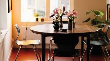A dining area with a round table, four chairs, and a vase with flowers.
