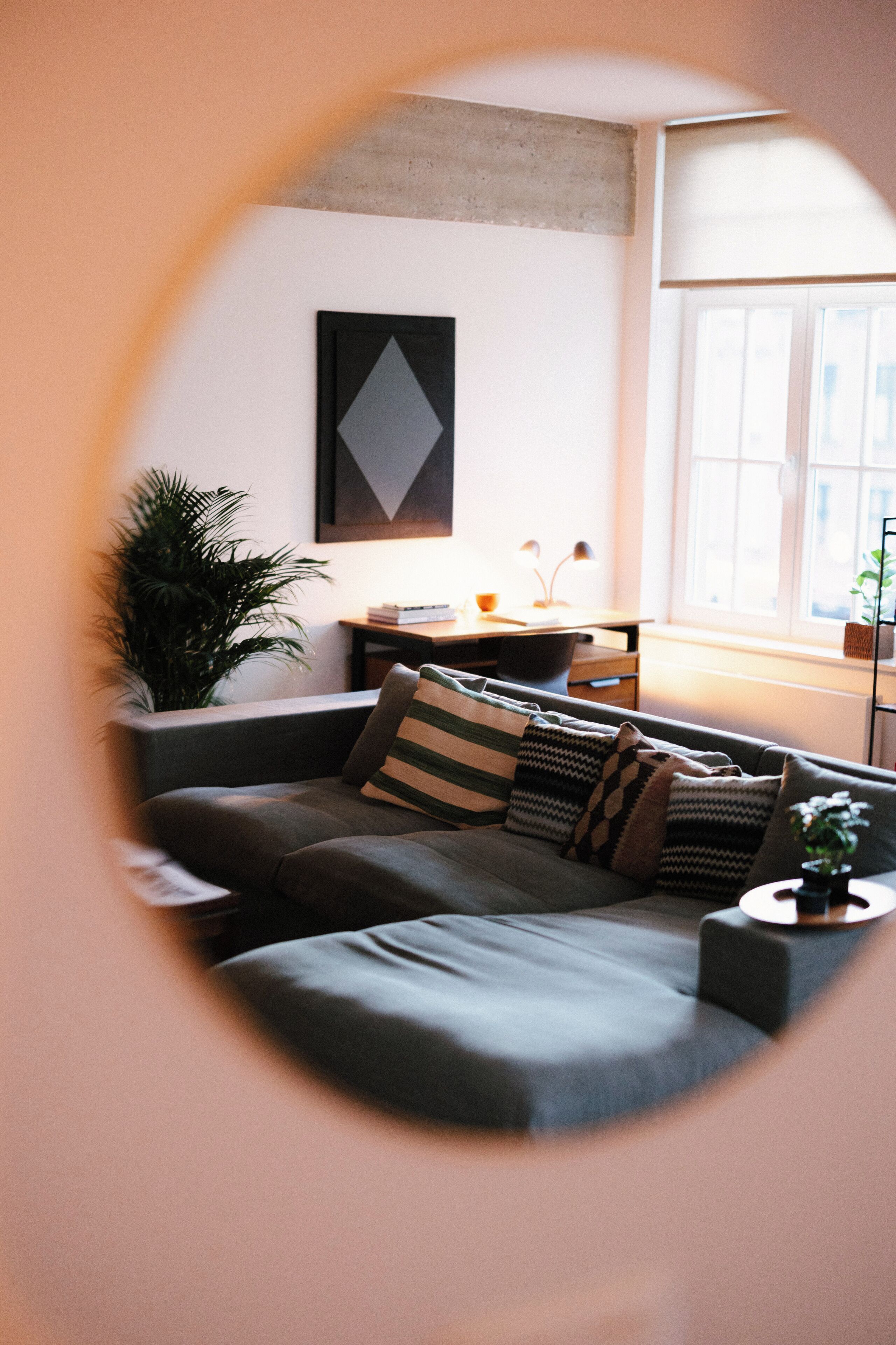 A cozy living room with a sectional sofa, a side table, a lamp, and a large window.