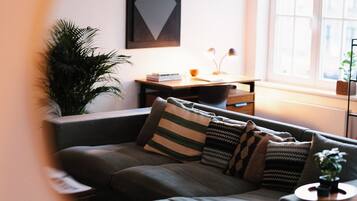 A cozy living room with a sectional sofa, a side table, a lamp, and a large window.