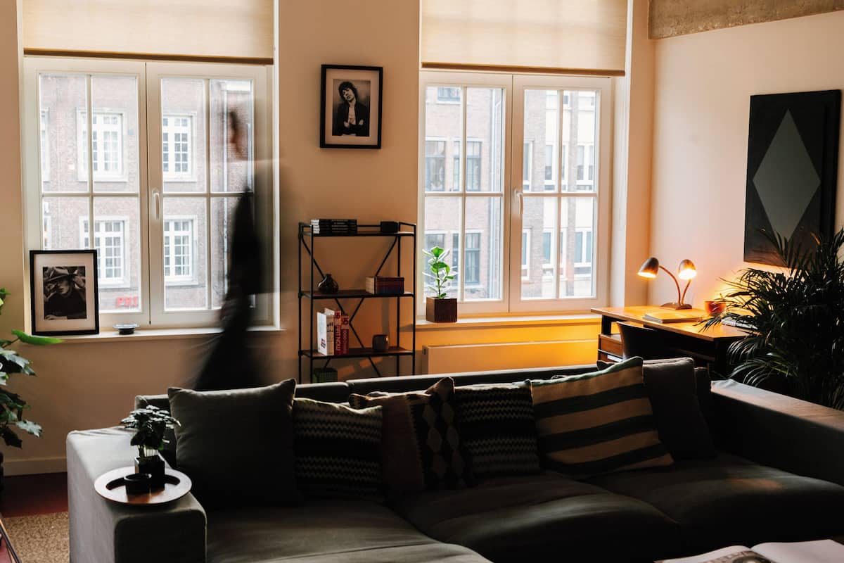 A cozy living room with a sofa, a bookshelf, and a desk with a lamp.