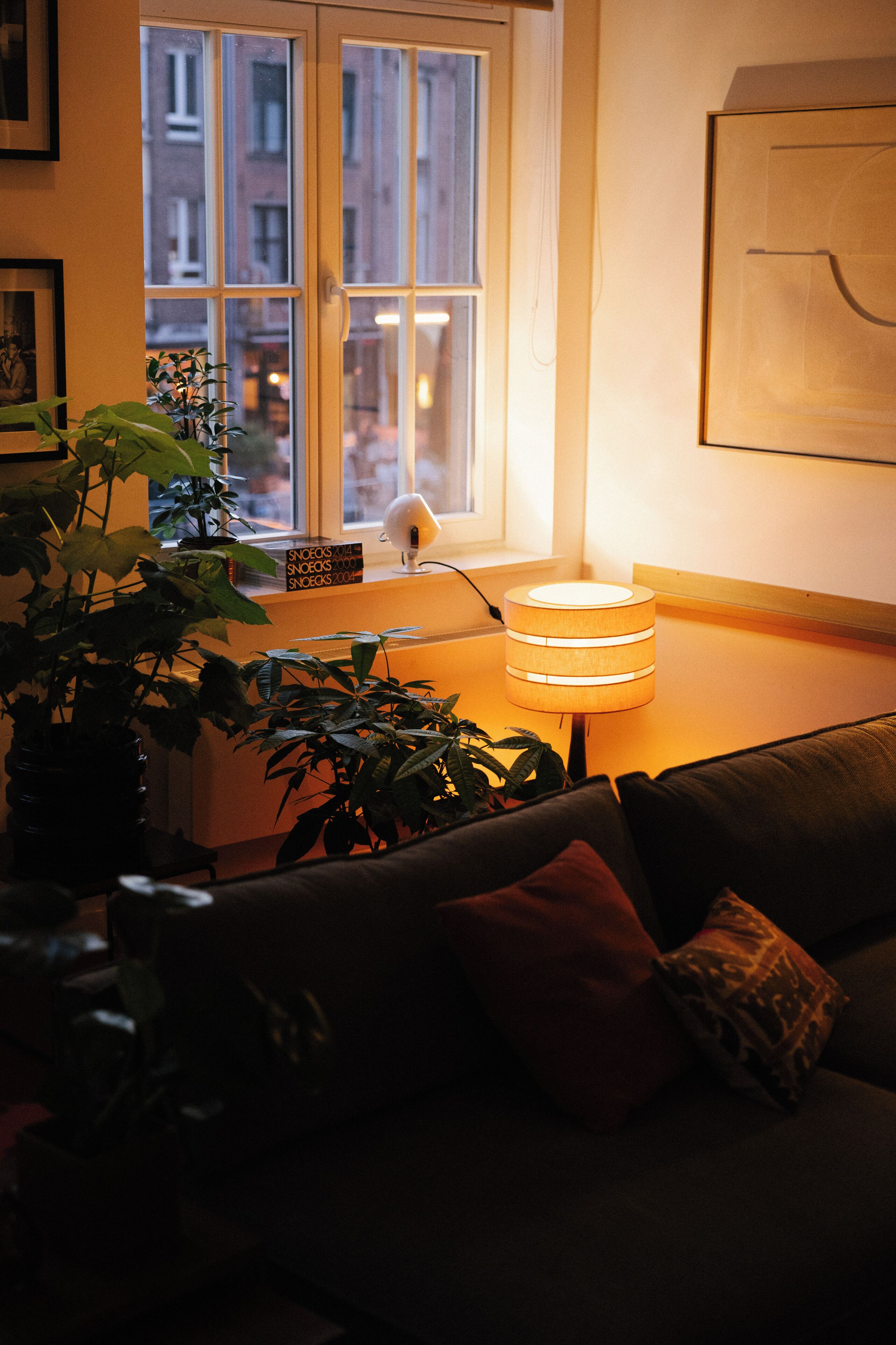 A cozy living room with a window, a lamp, and a couch.