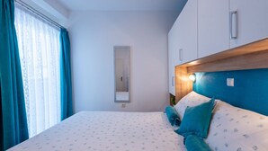 Een slaapkamer met een bed, een nachtkastje, een spiegel en een raam met gordijnen.