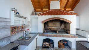 Een compacte keuken met een ingebouwde bakoven van baksteen, een spoelbak en een houten plafond.