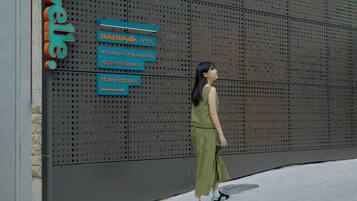 A woman walking past a hotel entrance sign with directions to the hotel and its address.
