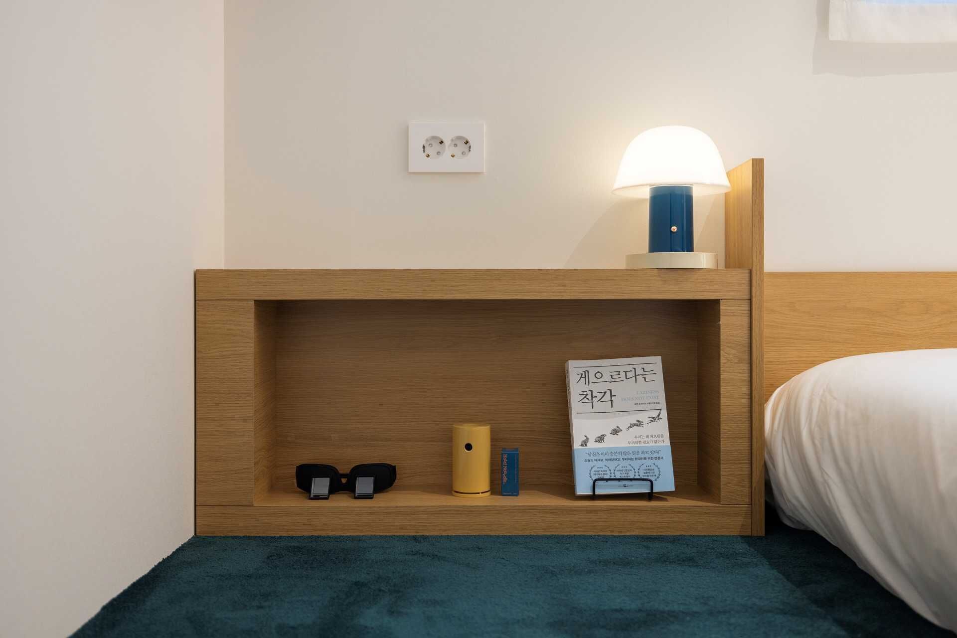 A neatly organized bedside table with a lamp, a pair of glasses, and a small box.