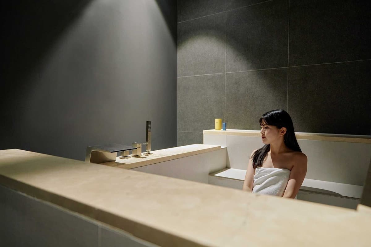 Un baño moderno con un espejo grande, un lavamanos y un perchero para toallas.