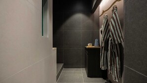 A narrow, dimly lit hallway with dark tiled walls and a small, dark-colored bench.