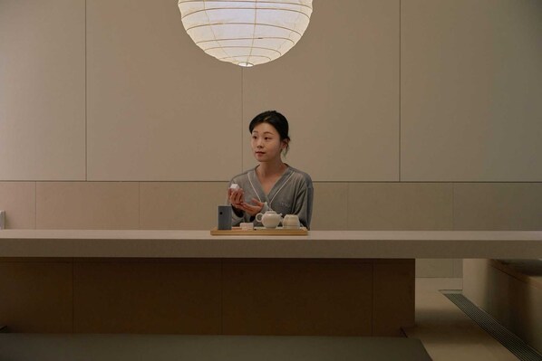 A reception desk with a person seated behind it, a teapot, and a cup on a tray. - Ondo Hotel and Spa Seoul Jongro (Seoul)