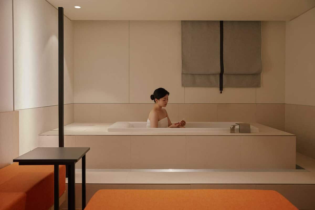 Une salle de bain moderne avec une grande baignoire, une petite table et un banc.
