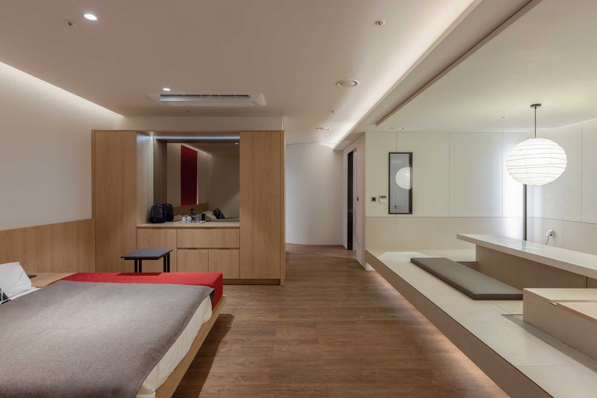 A modern hotel room with a bed, a desk, a mirror, and a large window.