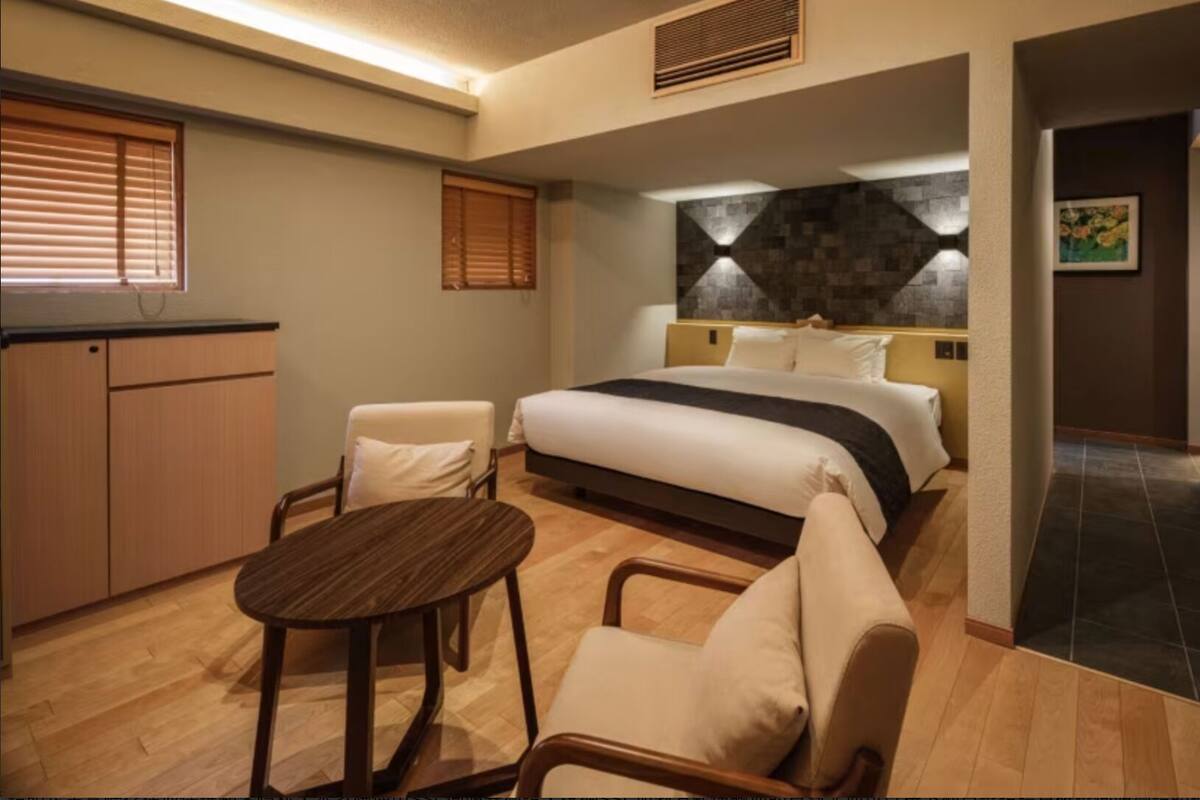 Een hotelkamer met een bed, een bureau, een stoel en een klein tafeltje.