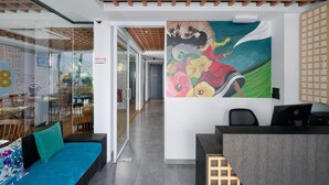 A modern reception area with a wooden ceiling, a colorful mural, and a seating area with a blue sofa.
