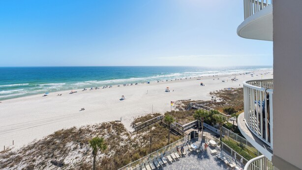 A beach view from a balcony with a clear sky, a sandy beach, and a calm sea. - Tradewinds 603 (Orange Beach)