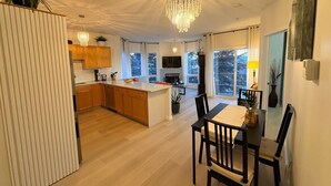 A modern kitchen with wooden cabinets, a central island, and a chandelier.