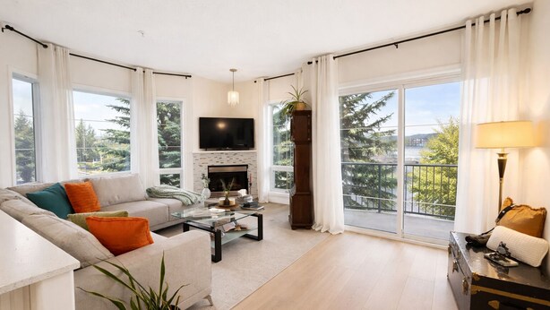 A modern living room with a sofa, coffee table, fireplace, and large windows with a view.