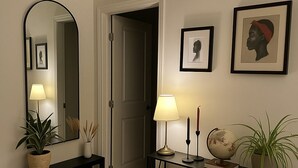 A hallway with a console table, a mirror, framed artwork, a globe, and potted plants.