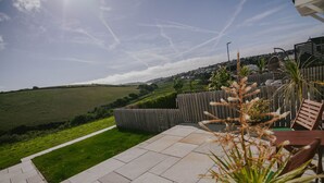 A patio area with a view of a green field and distant town. - Soak in amazing views @ EbbandFlow (Newquay)