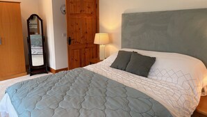 Une chambre à coucher avec un lit, une armoire en bois, un miroir et une horloge murale.