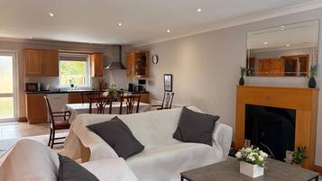 A modern living room with a sofa set, a dining table, and a fireplace.