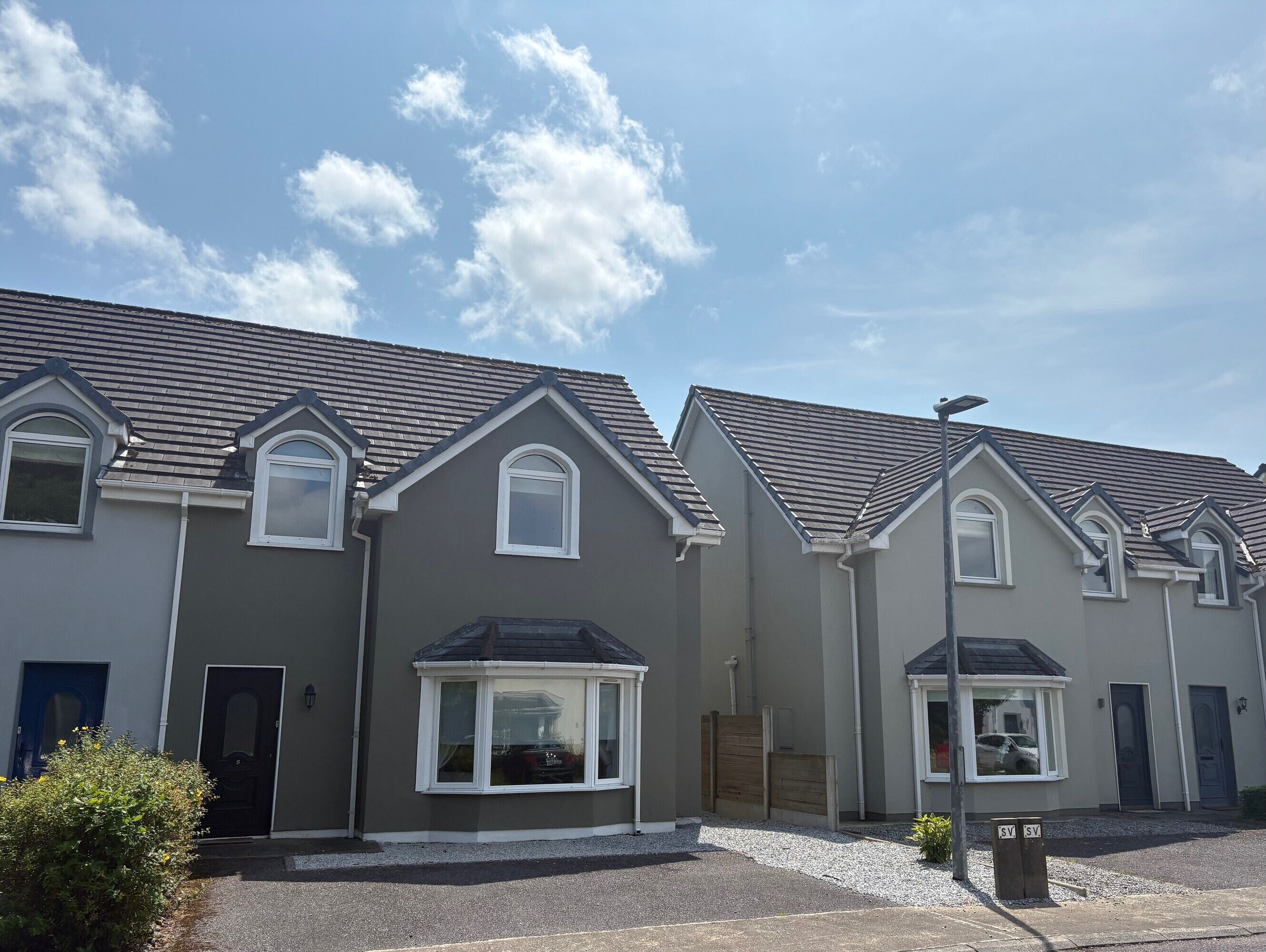 A row of modern houses with grey exteriors and pitched roofs.