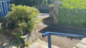 A stone staircase leading up to a gated entrance surrounded by lush greenery.