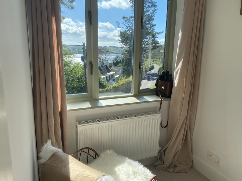 Ein Schlafzimmer mit großem Fenster, Heizkörper, Bett und Sessel.