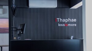 Una mesa de recepción con fondo negro y el texto "iThaphae less is more".