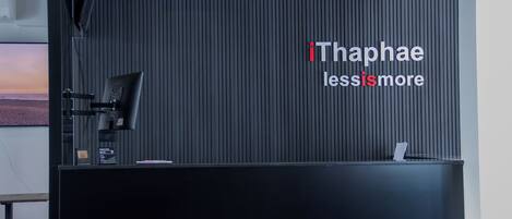 A reception desk with a black backdrop and the text "iThaphae less is more".