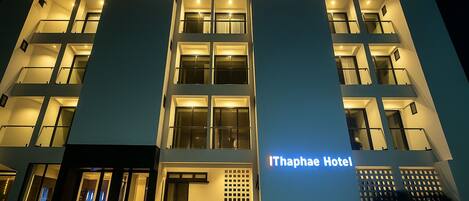 A modern hotel with a prominent entrance, multiple balconies, and a sign reading "Ithaphae Hotel".