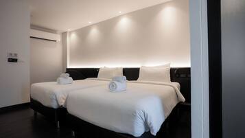 Habitación de hotel con dos camas, aire acondicionado de pared y cartel de no fumar.